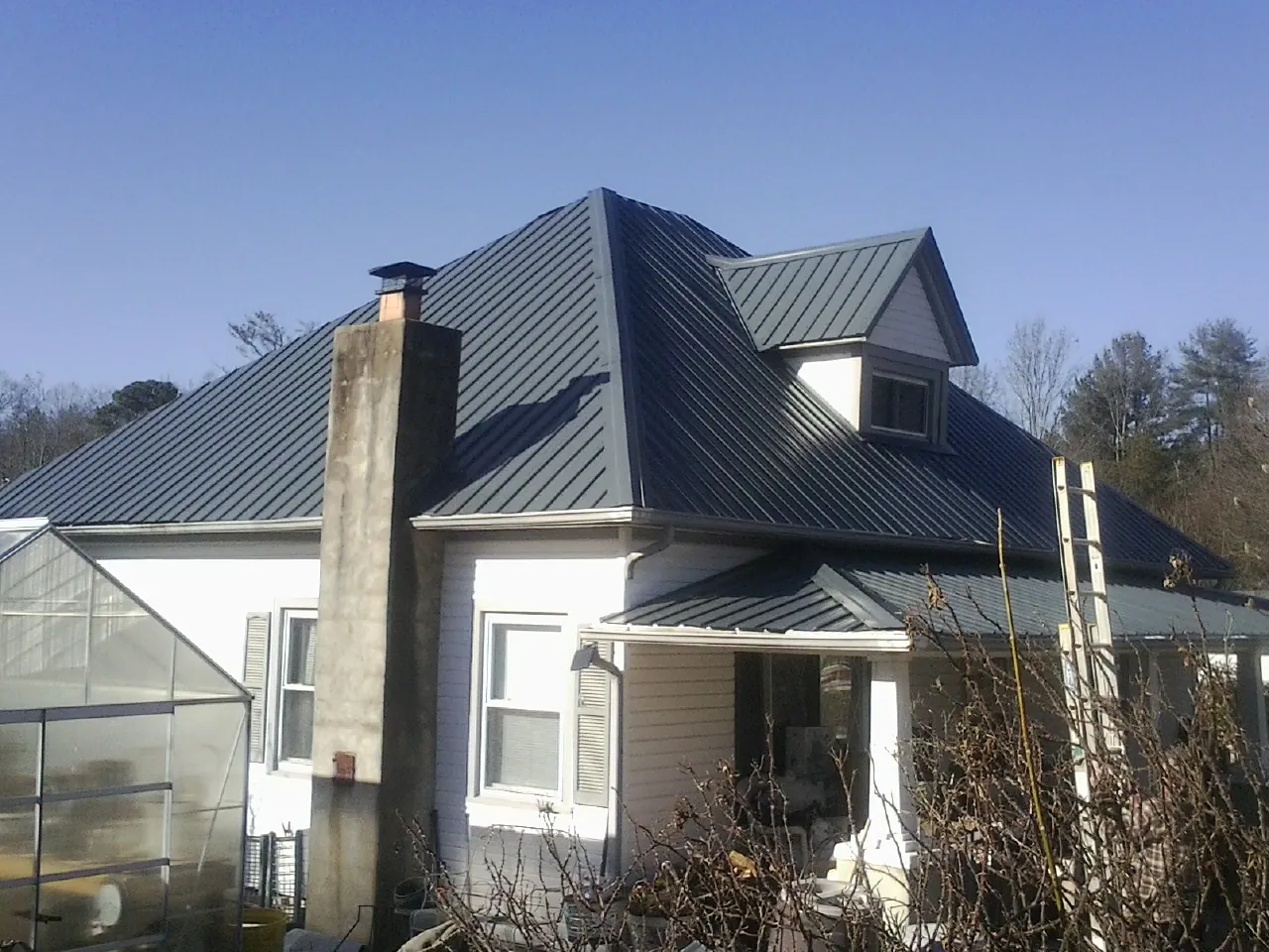 Dark blue standing seam metal roof on a white farmhouse with dormer — Slate & Tile Roof Repair by Roofing Brothers in Laguna Woods