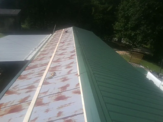 Old rusted panels beside newly installed green metal roofing — Wind Damage Roof Repair by Roofing Brothers in Laguna Woods