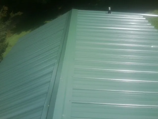 New green metal panels meeting at the ridge of a roof — Flat Roof Repair work by our crew in Laguna Woods