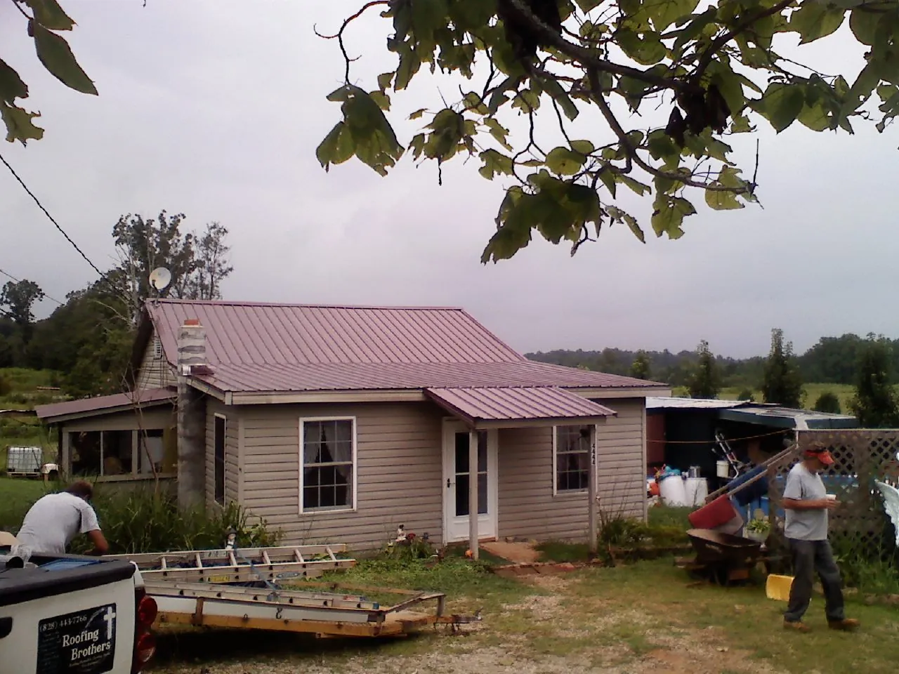 Crew finishing a mauve metal roof on a small farmhouse in Laguna Woods