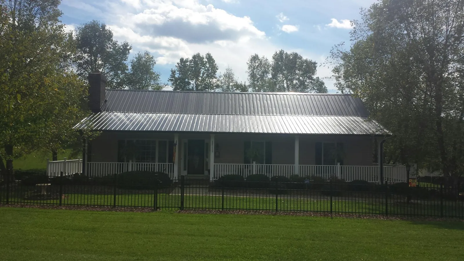 Gray metal roof on a brick ranch with a full width front porch — Gutter Guard Installation work by our crew in Laguna Woods