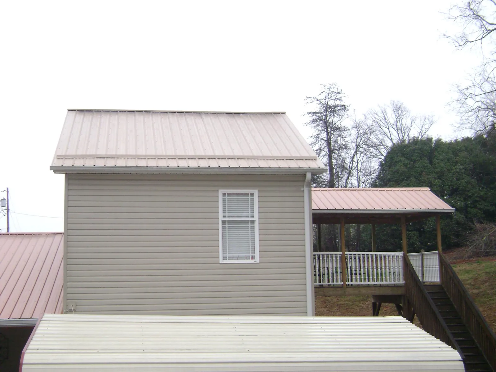 Tan metal roofs on a two story addition and attached porch, from a Roof Replacement job in Laguna Woods
