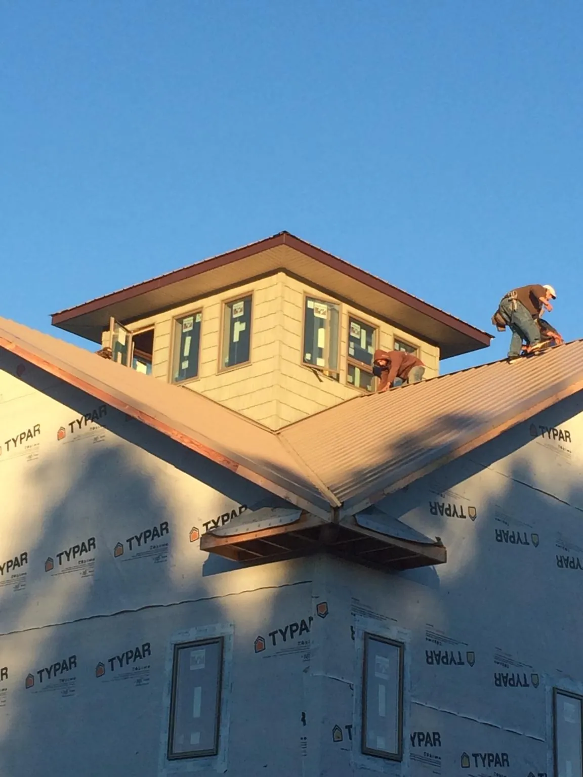 Roofers working around a rooftop cupola on a new metal roof at sunset — Roof Waterproofing in Laguna Woods by Roofing Brothers